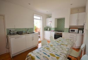 a kitchen with white cabinets and a table with chairs at Admirals Cottage in Yarmouth