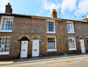 a brick building with white doors on a street at Admirals Cottage in Yarmouth