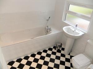 a bathroom with a bath tub and a sink and a toilet at Admirals Cottage in Yarmouth +17 photos
