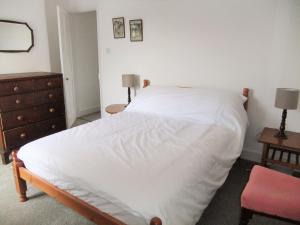 a bedroom with a white bed and a dresser at Admirals Cottage in Yarmouth