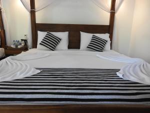 a bed with black and white striped sheets and pillows at Jungle Paradise in Udawalawe