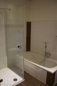 a glass shower in a bathroom with a tub at Hotel Zum Wersehof in Ahlen