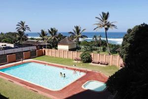 two people in a swimming pool with the ocean in the background at Sea Wave Holidays - Stella Maris in Amanzimtoti