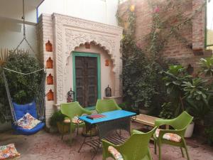 eine Terrasse mit Stühlen, einem Tisch und einer Tür in der Unterkunft Coral Country Homestay in Agra