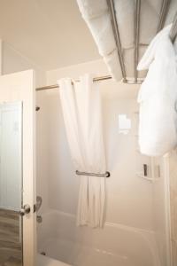 uma casa de banho com um chuveiro e toalhas brancas em Island Sun Inn & Suites - Venice, Florida Historic Downtown & Beach Getaway em Venice