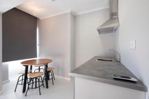 a small kitchen with a counter and stools in it at BUS STATION Suites & Studios in Coimbra