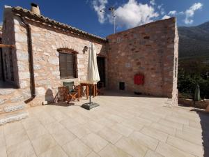 un patio exterior de un edificio de piedra con sombrilla en Guesthouse Toxotis, en Pyrgos Dirou
