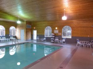 a swimming pool in a building with chairs and tables at Northwoods Best Inn - Chetek in Chetek