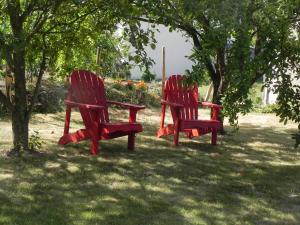 deux chaises rouges assises dans l'herbe sous un arbre dans l'établissement Les Patis, à Vouvray