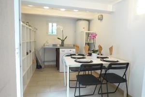- une cuisine avec une table et des chaises blanches dans l'établissement Le Cigalon, à Grasse