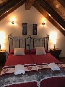 1 dormitorio con 1 cama roja y 2 toallas en Apartamentos Turisticos Lavedan, en Tramacastilla de Tena