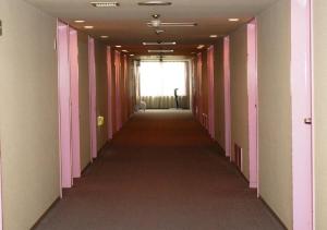 un largo pasillo con paredes rosas y blancas y una ventana en skyhotel uozu / Vacation STAY 59597, en Uozu