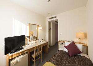 um quarto de hotel com uma secretária, uma cama e uma televisão em skyhotel uozu / Vacation STAY 59574 em Uozu