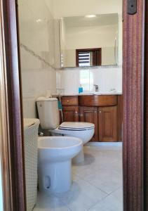 a bathroom with a toilet and a sink and a mirror at Edificio Lavadeiras in Olhão