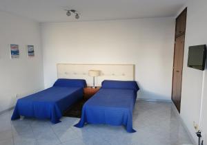 two beds with blue covers in a room at Edificio Lavadeiras in Olhão