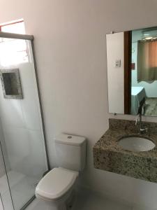 a bathroom with a toilet and a sink and a mirror at Hotel Alegrete in Alegrete