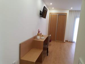 uma sala de estar com uma mesa e uma televisão num quarto em Residencial Dom Manuel em Fafe