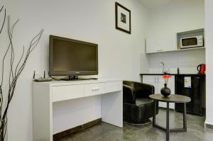 a living room with a television on a white desk at Geula Suites BY RAPHAEL HOTELS in Tel Aviv