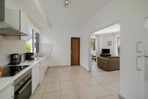 a kitchen with white appliances and a living room at Villa Amelia in Caniço
