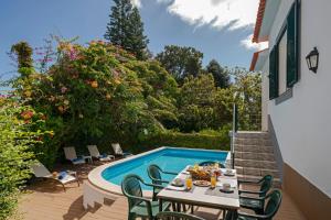 Un patio con mesa y sillas junto a una piscina. en Villa Amelia, en Caniço