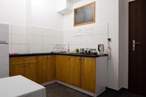 a kitchen with wooden cabinets and a chalkboard on the wall at Hostel Starówka in Zamość +29 photos
