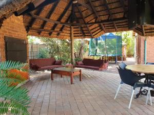 un patio con mesa, sillas y sombrilla en Accommodation@Bourne en Centurion