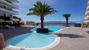 duży basen z palmą obok budynku w obiekcie Playa de la Arena Apartment w mieście Puerto de Santiago