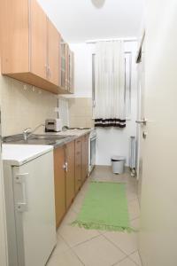 uma cozinha com armários de madeira e um tapete verde em Zap apartman em Belgrado