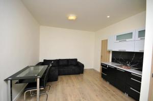 a living room with a black couch and a kitchen at Apartmány Mojžitov dvor in Lučenec