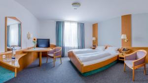 a hotel room with a bed and a desk with a computer at Hotel Parsberg in Puchheim