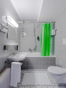 a bathroom with a green shower curtain and a toilet at Hotel Parsberg in Puchheim