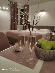 Aparthotel Cross Street 4 في ليوبليانا: كأسين من النبيذ على طاولة مع وعاء من الفاكهة