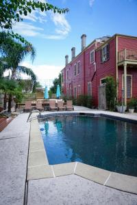 a swimming pool in front of a red building at Macarty House, A Bohemian Resort with pool and cabana bar in New Orleans