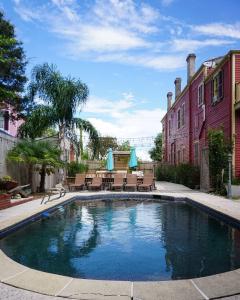 a swimming pool with tables and chairs in a yard at Macarty House, A Bohemian Resort with pool and cabana bar in New Orleans