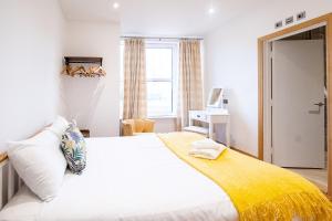 a bedroom with a bed with a yellow blanket on it at Three Tuns Apartments - Ash in Pettistree