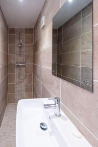 ein Bad mit einem Waschbecken und einer Dusche mit einem Spiegel in der Unterkunft Three Tuns Apartments - Sycamore in Pettistree
