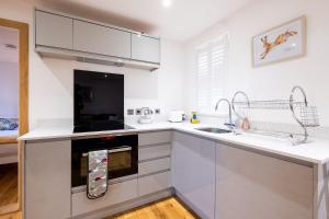 a white kitchen with a sink and a stove at Three Tuns Apartments - Sycamore in Pettistree