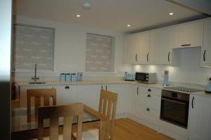 a kitchen with white cabinets and a table and chairs at The Final Furlong, Bruton in Bruton