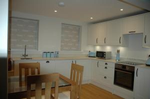 Una cocina con gabinetes blancos y una mesa y sillas. en The Final Furlong, Bruton, en Bruton