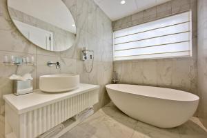 a bathroom with a large white tub and a mirror at HOLM Boutique & SPA - IK Collection in St. Julianʼs