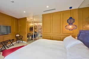 a bedroom with a white bed and a television at HOLM Boutique & SPA - IK Collection in St. Julianʼs