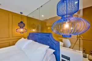 a bedroom with a bed with a blue headboard and lights at HOLM Boutique & SPA - IK Collection in St. Julianʼs