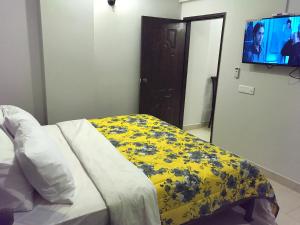a bedroom with a bed with a yellow blanket and a flat screen tv at "Service Apartments Karachi" Ocean View 2 Bed Room Apt in Karachi