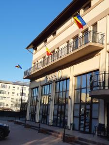 a building with two flags on top of it at Hotel Ro&Mario Barlad in Bîrlad