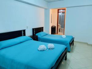 two beds with blue sheets in a room with a mirror at VIVIENDA TURÍSTICA EL ZÓCALO in Guatapé