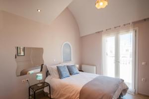 a bedroom with a large bed with blue pillows at Veldi Art - Kamari Beach Apartment in Fira