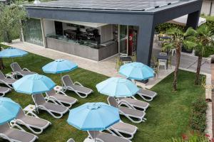 grupa krzeseł i niebieskich parasoli na trawie w obiekcie Residence Villa Rosa w mieście Garda
