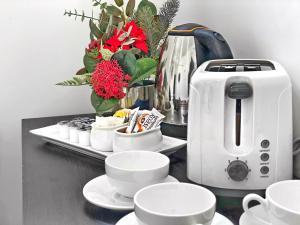 a counter with cups and a coffee maker and flowers at Commercial Motel in Hay