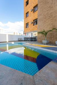 uma piscina com piso de azulejo colorido e um edifício em Hotel Carlton Plaza em Poços de Caldas