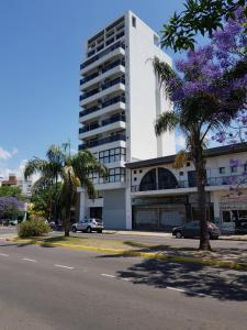 拉普拉塔的住宿－Acogedor monoambiente La Plata centro，一条街道前方有紫色花卉的高层建筑